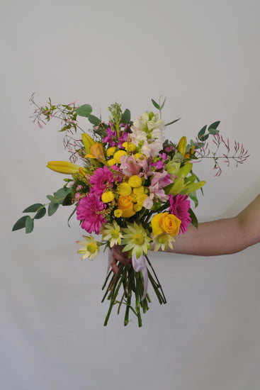 Bouquet of colorful flowers held by a person against a plain background